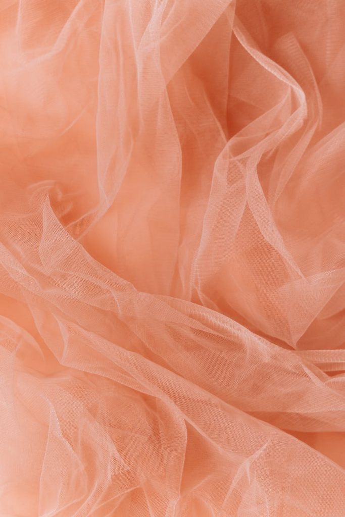 Delicate orange sheer fabric with soft folds, ideal for backgrounds or mobile wallpapers.