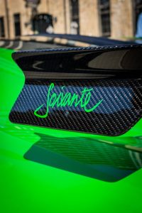 Close-up of a green sports car spoiler with carbon fiber texture.