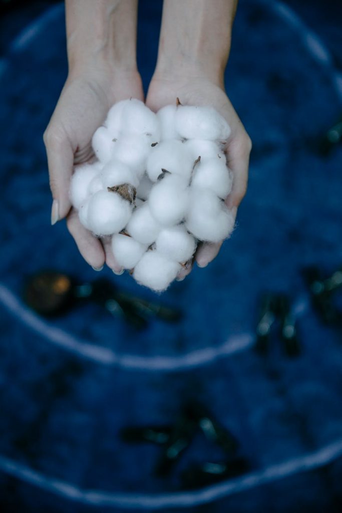 Carbon Fiber Fabric: Must-Have Guide to Its Amazing Creation Hands gently cradle fresh cotton bolls against a vibrant blue background.