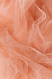 Delicate orange sheer fabric with soft folds, ideal for backgrounds or mobile wallpapers.